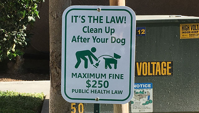 Friendly reminder to pick up after your dog sign.